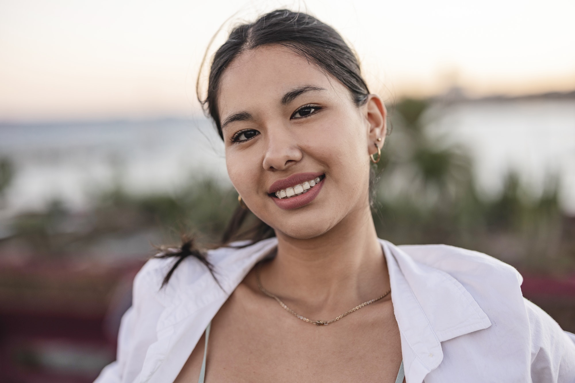 Close up portrait of a smiling asian young female near the sea