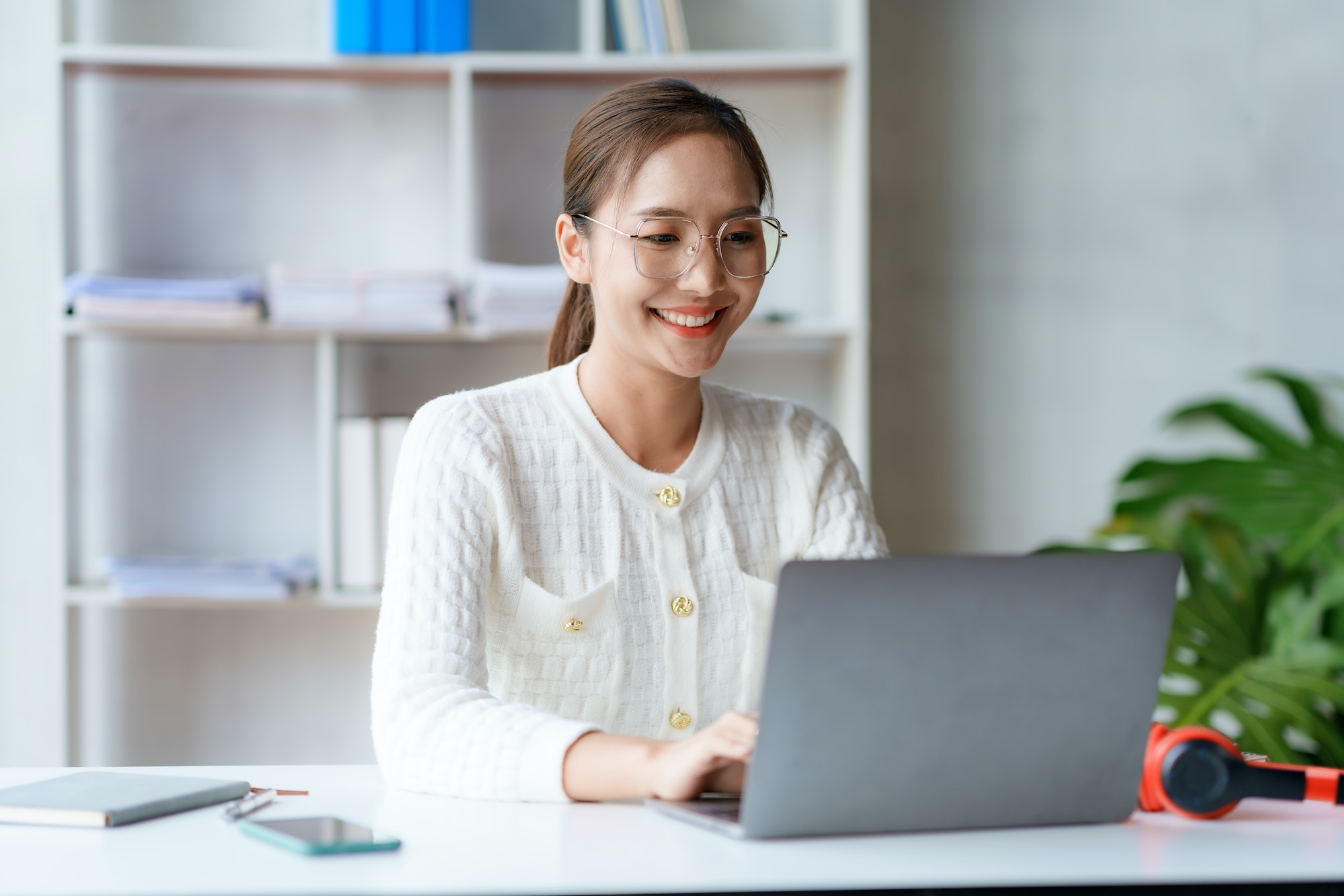 Cute young Asian woman sitting at cafe with her laptop happily. Asia female working on laptop comput